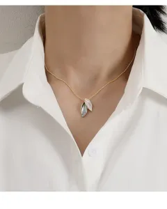 Detailed view of an elegant leaf pendant necklace with a gold chain on a model