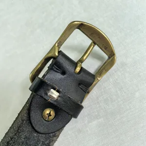 Primo piano dettaglio fibbia per cintura ad ardiglione in ottone massiccio vintage accessorio.