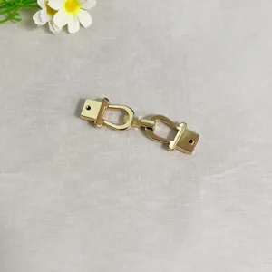 Dettaglio fibbia doppia in metallo dorato, elegante accessorio per borse e abbigliamento.