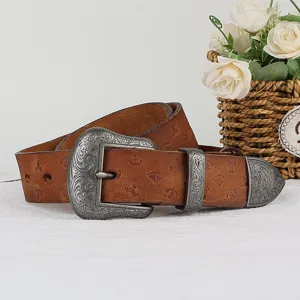 Vintage leather belt detail showing ornate embossed metal buckle and carved western patterns.
