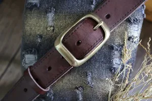 Primo piano dettagliato di una cintura in pelle marrone vintage con fibbia ad ardiglione in metallo.