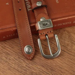 Close-up of vintage brown leather belt featuring intricate metal buckle and retro carved decorative studs.