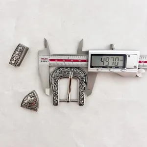 Detailed view of vintage zinc alloy carved belt buckle set with caliper measurement view.