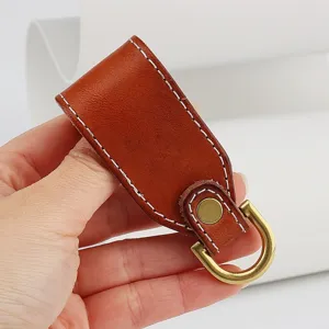 Detail shot of genuine leather belt key holder loop with brass hardware and white stitching.