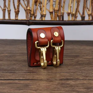 Close-up of brown leather key holder with brass hooks and metal snaps for belt attachment.