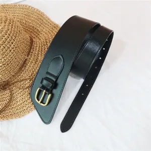 Detailed view of the black wide waist belt with a stylish metal buckle and chic pointed end.