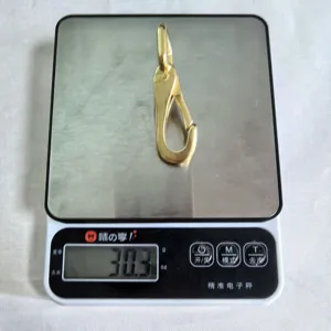 Detailfoto van de metalen karabijnhaak op een digitale weegschaal met 30,3 gram.