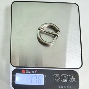 Close-up detail of metal round pin belt buckle showing product weight and hardware texture.