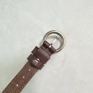 Women's vintage brown leather belt with round metal buckle and star rivets detail.