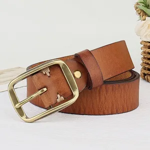 Close-up detail of retro genuine leather belt with brass pin buckle and handmade stitching.