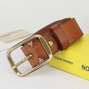 Close-up detail of retro brown leather belt with brass buckle and hand stitching on display.