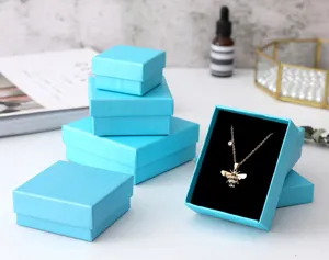 Detailopname van hemelblauwe linnen textuur juwelendoosjes met een bijenketting.