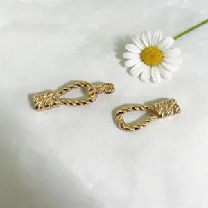 Golden alloy twisted buckle detail, elegant metallic shine for clothing and accessory design.