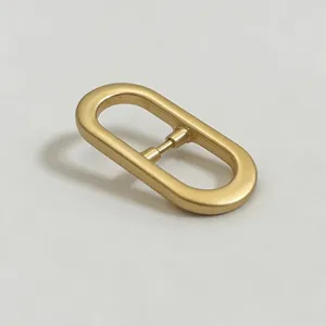 Matte gold metal oval belt buckle detail, premium hardware for bags and garments.