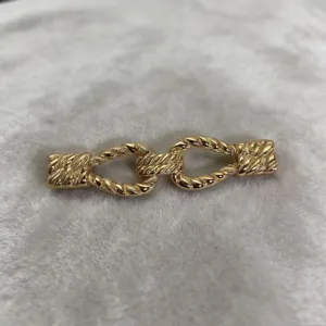 Detail view of a gold alloy twisted rope apparel buckle accessory, showing exquisite texture.