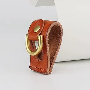 Close-up detail of handmade vegetable-tanned leather belt loop key holder with brass ring.