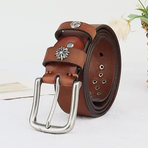 Close-up detail of vintage brown genuine leather belt with metallic buckle and floral rivets.