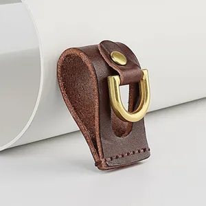 Detailed view of handmade brown leather belt loop with brass d-ring and snap button.