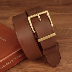 Macro view of classic brass square buckle on a premium brown stitched leather belt.