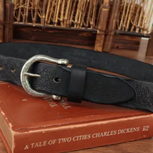 Detailed view of genuine leather belt with vintage floral embossing and retro metal buckle.
