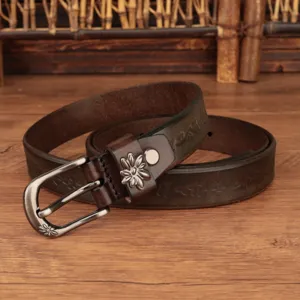 Primo piano di una cintura in pelle vintage marrone con incisioni floreali e fibbia