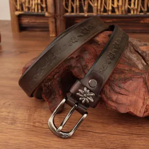 Dettaglio di cintura vintage in pelle con fiori goffrati su sfondo di legno rustico