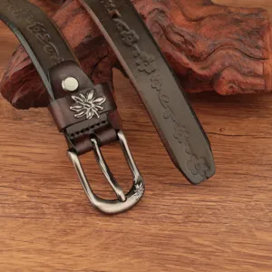 Primo piano di cintura in pelle marrone vintage con intagli floreali e fibbia in metallo