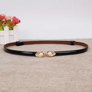 Smalle zwarte laklederen riem met een elegante gouden parelgesp voor damesmode.