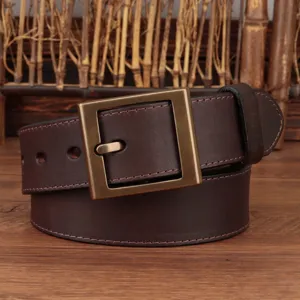 Primo piano dettagliato della cintura in pelle marrone scuro vintage con fibbia quadrata in ottone.