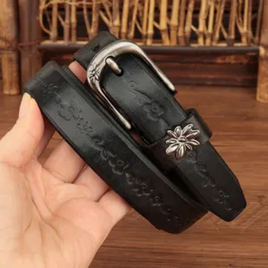 Primo piano di una cintura vintage in pelle nera con motivi floreali a rilievo