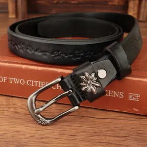 Dettaglio cintura in pelle nera vintage con goffratura floreale e fibbia in metallo.