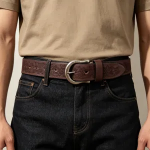 Close-up of vintage embossed genuine leather belt with metallic buckle on dark jeans.