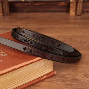 Detail shot of a dark brown leather thin belt with hollow cross patterns on vintage book.