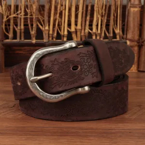 Close-up detail of vintage floral embossed genuine leather belt with retro metal buckle texture.