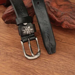 Dettaglio di cintura in pelle nera con incisioni floreali e fibbia in argento vintage.