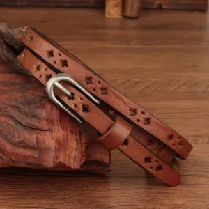 Close-up detail of genuine leather thin belt with star cutouts and metal buckle on rustic wood.