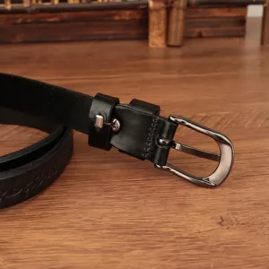 Vista dettagliata di una cintura in pelle vintage nera con fibbia metallica su legno.