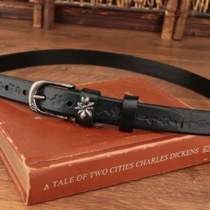 Dettaglio cintura vintage in pelle nera con goffratura floreale e fibbia argento