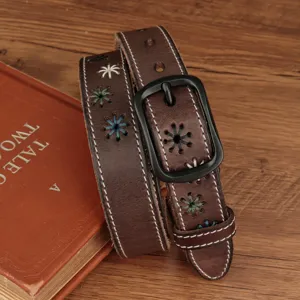 Close-up of brown leather belt with vintage embroidered flowers and black buckle