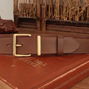 Close-up of classic brown genuine leather belt with elegant brass square buckle.
