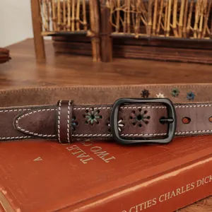 Detail of a vintage brown leather belt featuring floral embroidery and a matte black buckle