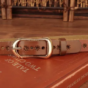 Dettaglio di cintura da donna in pelle marrone con fibbia dorata e intagli a stella.