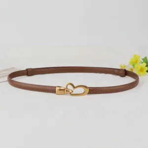 Slim genuine leather belt for women featuring a vintage gold heart buckle. Detail view.