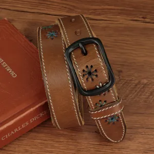 Close-up of vintage brown leather belt with blue flower embroidery and black buckle.