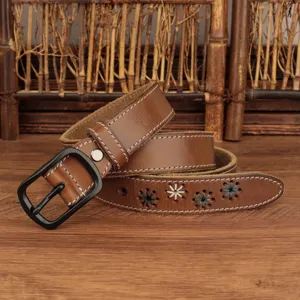 Detailed view of brown leather belt with floral embroidery and matte black buckle