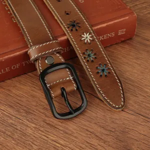 Close-up detail of brown leather belt with embroidered flower patterns and black buckle