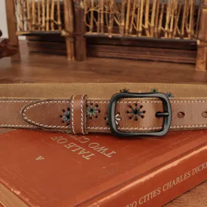 Close-up of brown leather belt with decorative stitching and black metal buckle