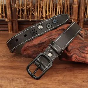 Close-up detail of a black leather belt with white stitching and floral star pattern accents