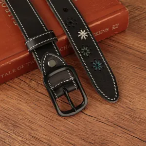 Close-up of black leather belt featuring colorful flower embroidery and white contrast stitching.