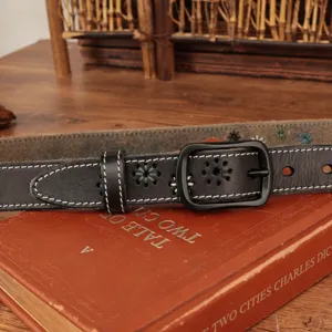 Close-up of a black vintage leather belt with floral embroidery and white stitching